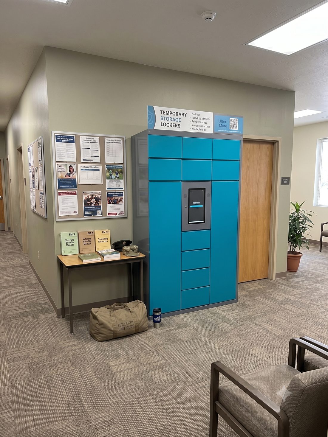 A SafeReach locker bank installed in a public building hallway beside a community notice board.